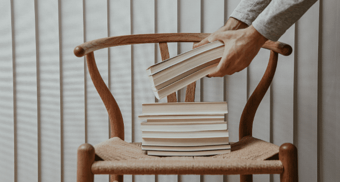 a photo of someone putting a stack of books on a chair